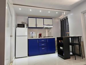 cocina con nevera blanca y armarios azules en Nala's Studio, en Mayagüez