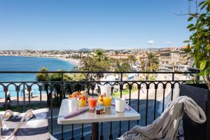 a table with drinks on a balcony with a view of the beach at Hotel Suisse in Nice
