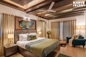 a bedroom with a large bed and a blue chair at StayVista's Grace & Light - Hill-view villa with Outdoor pool, Terrace & Games room in Panchgani +21 photos