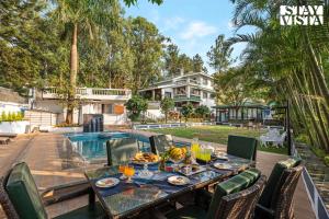 a table with food and drinks on a patio with a pool at StayVista's Grace & Light - Hill-view villa with Outdoor pool, Terrace & Games room in Panchgani