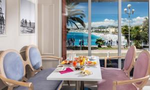 een tafel met eten erop met uitzicht op het strand bij Hotel Suisse in Nice
