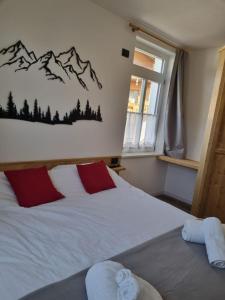 um quarto com uma cama branca e almofadas vermelhas em Appartamento Vale e Schena Cortina 4 posti letto em San Vito di Cadore