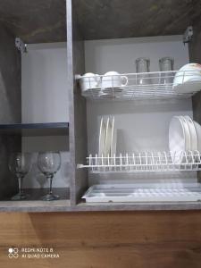 una estantería con platos y copas de vino en la cocina en Квартира-студия в мкр Аэропорт, en Kostanái
