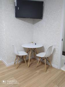 mesa blanca, 2 sillas y TV. en Квартира-студия в мкр Аэропорт, en Kostanái