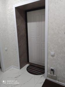 una puerta blanca con una alfombra negra delante de ella en Абсолютно новая квартира en Kostanái