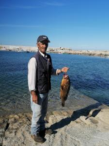 un uomo in piedi in acqua con un pesce di oasis studio a Diafani