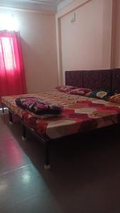1 cama grande en un dormitorio con cortina roja en Mishra ji, Contact on 97542-41466, en Ujjain
