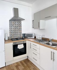 利物浦的住宿－3 Bedroom House near Liverpool Football Stadium，厨房配有白色橱柜和炉灶烤箱。