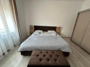 a bedroom with a bed and a brown ottoman at Aparthouse in Lugoj