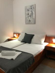 een slaapkamer met 2 bedden en 2 nachtkastjes bij Apartmani Samec in Novalja