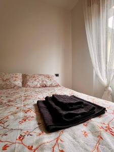 um roupão preto deitado em cima de uma cama em Perla house em Abbadia Lariana