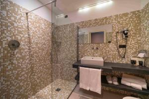 ein Bad mit einem Waschbecken und einer Glasdusche in der Unterkunft Piajo Relax Hotel in Nembro
