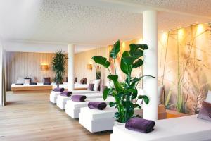 a living room with white couches and a plant at Hotel Deimann in Schmallenberg