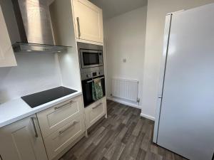 cocina con armarios blancos y nevera en Urban Escape Entire Apartment Near Uni and Hospital, en Southampton