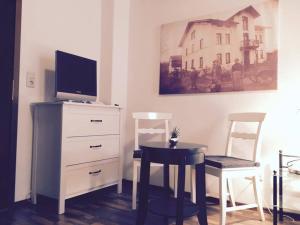 ein Wohnzimmer mit einem TV, einem Tisch und Stühlen in der Unterkunft Zur Dorfschänke DEGGENDORF Ferienwohnung,Apartment, Hotelzimmer in Deggendorf