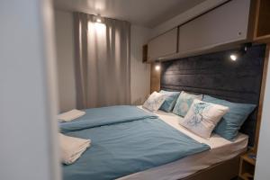 een slaapkamer met een groot bed met blauwe lakens en kussens bij Adriakamp Mobilehome - Camp Soline in Biograd na Moru