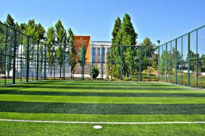 a batting cage on a tennis court in front of a building at Arena Sport Hotel in Quba