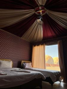 瓦迪拉姆的住宿－Rise Camp Wadi Rum，一间卧室设有两张床和一个享有沙漠美景的窗户。