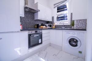 a kitchen with white cabinets and a washer and dryer at Luxurious Apartments on Oxford Street in London