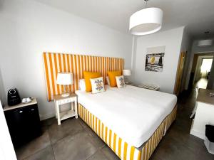 a bedroom with a bed with an orange and white striped headboard at Hotel HS Milfontes Beach - Duna Parque Group in Vila Nova de Milfontes