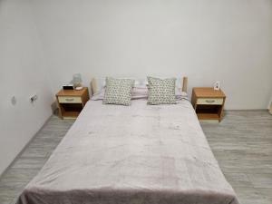 een groot bed in een kamer met 2 tafels bij Apartman Kućica u cveću in Jagodina