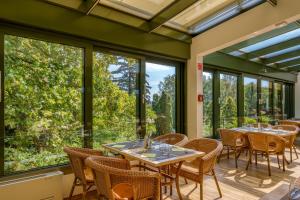 comedor con mesas y sillas y ventanas grandes en Ensana Thermal Aqua, en Hévíz