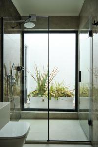 La salle de bains est pourvue d'une porte de douche en verre avec une plante en pot. dans l'établissement Ashta Gold Suite, à Fethiye