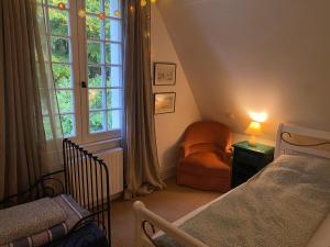a bedroom with a bed and a chair and a window at La Maison du Gardien, Chateau de lAvenue in Pierrefitte-en-Auge