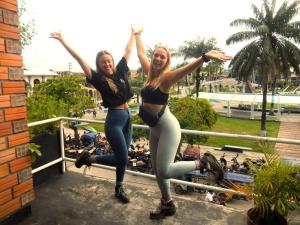 two women standing on a balcony with their arms in the air at Hospedaje Neydita in Iquitos