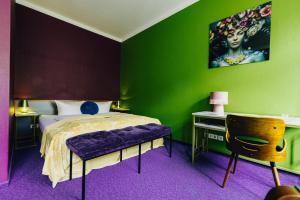 ein Schlafzimmer mit grünen Wänden und einem Bett mit einem lila Sitz in der Unterkunft Boutique Hotel Rothenburger Hof in Dresden