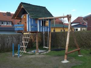 a tree house with a ladder and a swing at Bungalow am Fleesensee in Unter Göhren