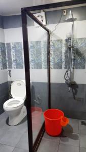 a bathroom with a toilet and a red bucket at Backwater Breeze in Kumarakom