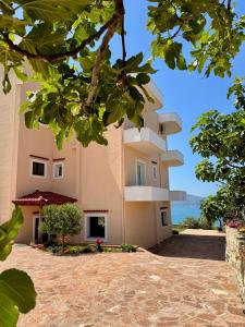 a large pink building with trees in front of it at Levi's Villa Radhima in Vlorë