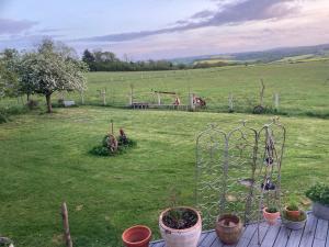 a garden with potted plants and a fence in a field at Cottage with Hot Tube & private Sauna with panoramic view in Les Moutiers-en-Cinglais