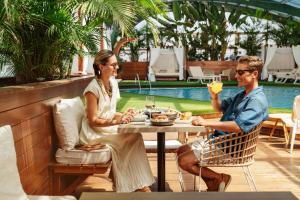 a man and woman sitting at a table by a pool at Arrecife Gran Hotel & Spa in Arrecife