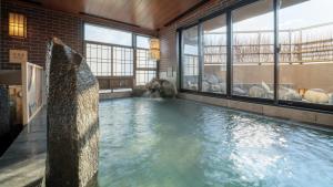 a large swimming pool in a building with windows at Dormy Inn Morioka in Morioka