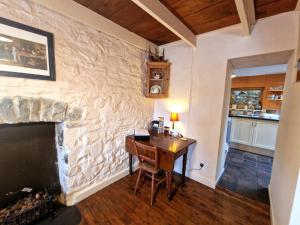 a room with a stone wall with a desk and a fireplace at Arwel Nanternis in Llanllwchaiarn