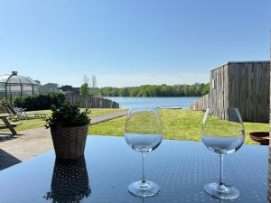 two wine glasses sitting on a table with a view of a lake at Haus am See in Barßel