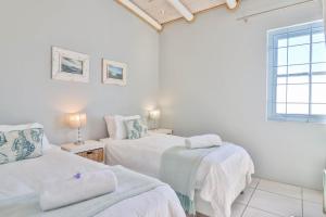 a white room with two beds and a window at Tides Holiday Home in Paternoster