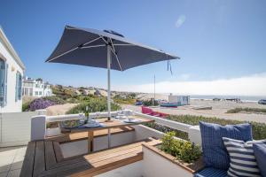 a patio with a table and an umbrella at Tides Holiday Home in Paternoster