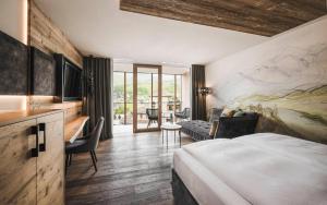 une chambre d'hôtel avec un lit et un salon dans l'établissement Excelsior Dolomites Life Resort, à San Vigilio Di Marebbe