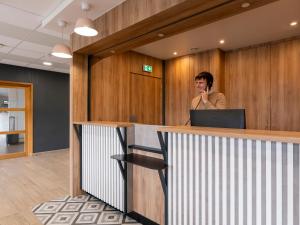 a man talking on a cell phone at a reception desk at B&B HOTEL Lorient Ploemeur in Ploemeur