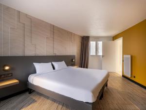 een slaapkamer met een groot wit bed in een kamer bij B&B HOTEL Lorient Ploemeur in Ploemeur