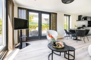 a living room with a flat screen tv and a table at Nieuw vakantiehuis Domburg, in centrum dichtbij strand in Domburg