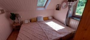una piccola camera da letto con un letto e un piumone rosa di Erdőterasz Vendégház - Erdei Apartman a Kehidakustány