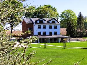 a large white house on a green lawn at Trzy Fale in Dąbrówno