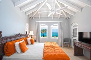 - une chambre avec un lit doté d'oreillers orange et d'un ventilateur de plafond dans l'établissement Villa Mongoose - vue exceptionnelle, à Saint-Martin