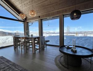 une salle à manger avec une table et une grande fenêtre dans l'établissement Golsfjellet - new modern cabin with fantastic view, à Golsfjellet