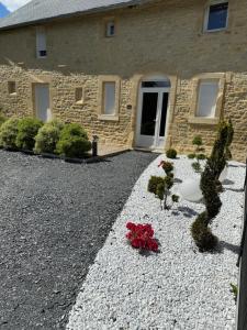 a stone house with flowers in front of it at "l'Escape room" - love room atypique in Saint-Martin-des-Entrées