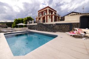 a swimming pool in front of a house at B&B Badimà in Fleri
